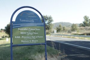 Tamworth town sign listing regional awards: Australia’s Tidiest Town and NSW Tidiest Town, plus Premiers’ Hall of Fame and Nations In Bloom on a roadside sign